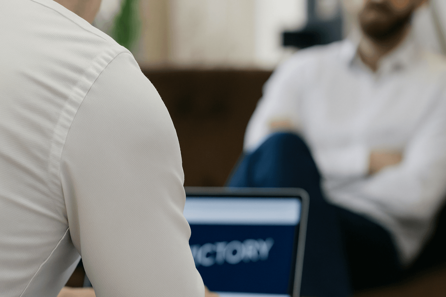 Two professionals in a modern office discussing PPC campaign strategy over a laptop